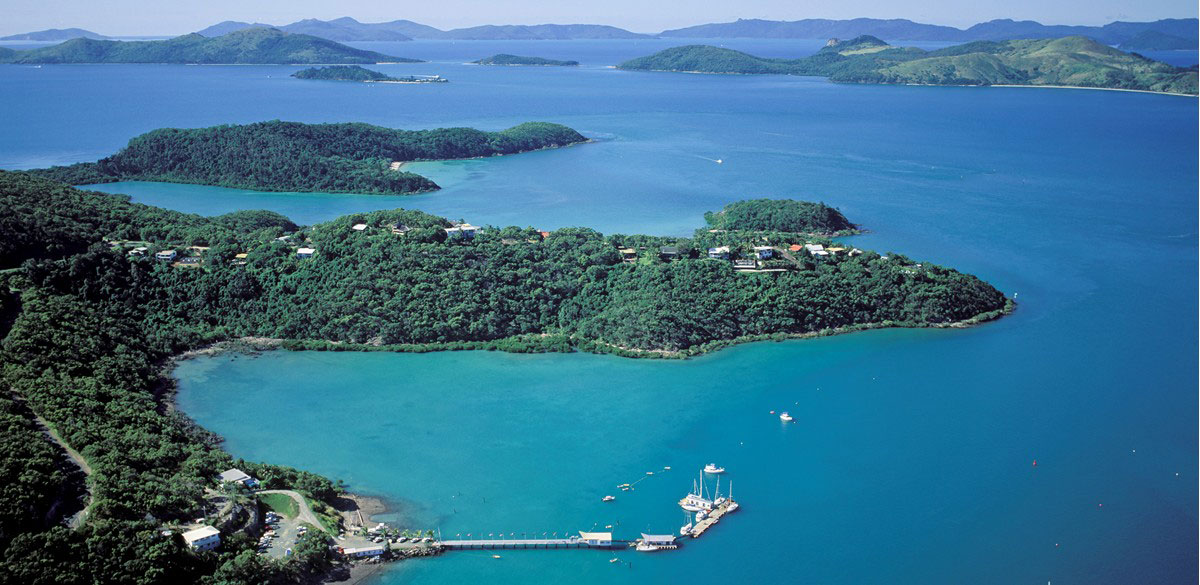 Aerial view of Shute Harbour and surrounding coast and islands with the Whitsunday Rent A Yacht jetty in the foreground