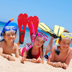 Three children lying on Chalkies Beach in snorkels, masks and flippers